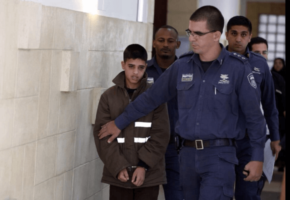 AHMAD MANASRA, 13-YEARS-OLD AT THE TIME, BEING LED BY ISRAELI AUTHORITIES IN A DETENTION FACILITY (SOURCE: TWITTER)
