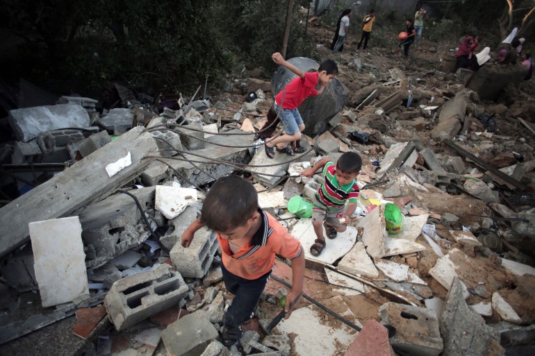 Palestinian children walk in the rubble of a house destroyed by an Israeli strike in the town of Beit Hanoun, northern Gaza Strip, in 2014 [File: Khalil Hamra/AP]